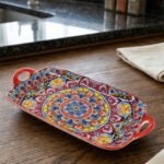Vibrant 13-inch decorative Marrakech ceramic serving dish with colorful mosaic patterns and built-in side handles displayed on a wooden countertop.