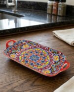 Vibrant 13-inch decorative Marrakech ceramic serving dish with colorful mosaic patterns and built-in side handles displayed on a wooden countertop.
