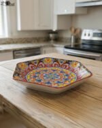 Hexagonal decorative Marakesh plate with vibrant hand-painted Moroccan tile mosaic pattern on a wooden kitchen table.