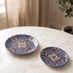 Two vibrant blue, yellow, and red decorative Marrakech ceramic plates displaying intricate mosaic patterns on a white marble surface in 8-inch and 10-inch sizes.