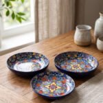 Decorative ceramic bowls with traditional Marrakech hand-painted designs on a rustic wooden dining table.