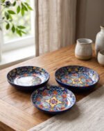 Decorative ceramic bowls with traditional Marrakech hand-painted designs on a rustic wooden dining table.