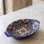 9.5-inch decorative Marrakech oval ceramic serving bowl with intricate blue, orange, and yellow hand-painted floral patterns resting on a marble countertop