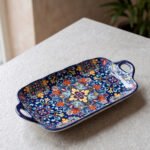 Intricate vibrant blue and yellow Marrakech ceramic serving dish tray with built-in handles on a stone countertop