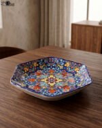 Decorative Marrakesh ceramic serving dish with colorful Moroccan mosaic pattern resting on a wooden dining table.