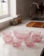 7-piece grey ribbed glass fruit set featuring one large serving bowl and six small bowls with elegant gold rims, displayed on a kitchen counter.