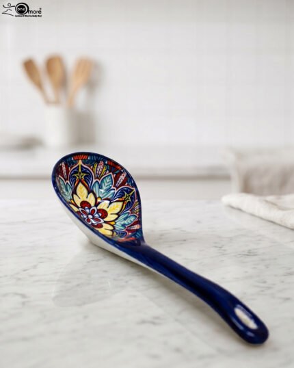 Handcrafted decorative Marrakech ceramic spoon with vibrant blue, yellow, and red bohemian floral patterns resting on a marble countertop