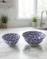 Pair of decorative blue and white Marrakesh ceramic floral bowls in 6-inch and 8-inch sizes sitting on a marble kitchen countertop.