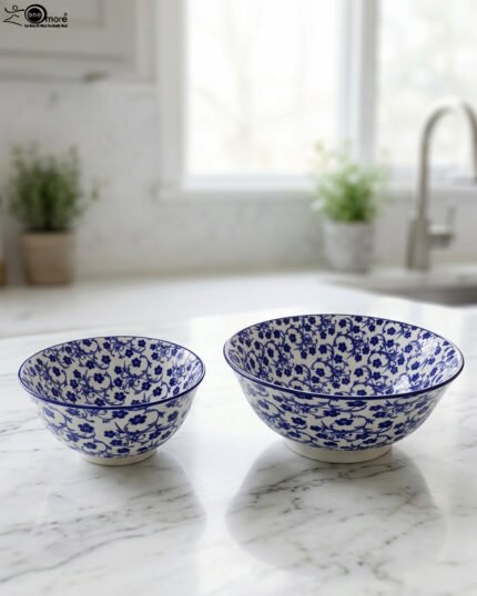 Pair of decorative blue and white Marrakesh ceramic floral bowls in 6-inch and 8-inch sizes sitting on a marble kitchen countertop.