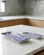 Two rectangular blue and white decorative Marrakesh serving dishes in 8-inch and 10-inch sizes displayed on a marble countertop.