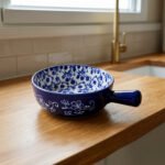 Decorative 6-inch blue and white floral ceramic Marakesh serving dish with single side handle on a wooden kitchen countertop.