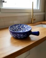 Decorative 6-inch blue and white floral ceramic Marakesh serving dish with single side handle on a wooden kitchen countertop.