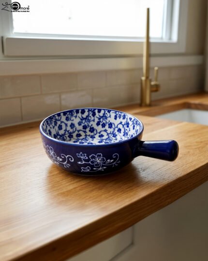 Decorative 6-inch blue and white floral ceramic Marakesh serving dish with single side handle on a wooden kitchen countertop.