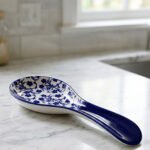 Blue and white ceramic spoon rest with Moroccan floral pattern resting on a marble countertop.