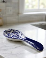 Blue and white ceramic spoon rest with Moroccan floral pattern resting on a marble countertop.
