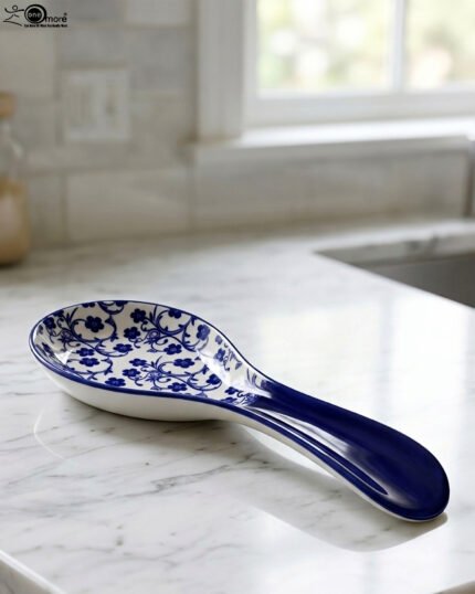 Blue and white ceramic spoon rest with Moroccan floral pattern resting on a marble countertop.