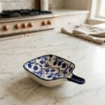 Square ceramic Moroccan dip bowl with blue floral patterns and integrated handle resting on a light marble kitchen countertop.