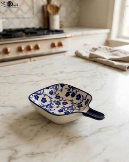 Square ceramic Moroccan dip bowl with blue floral patterns and integrated handle resting on a light marble kitchen countertop.