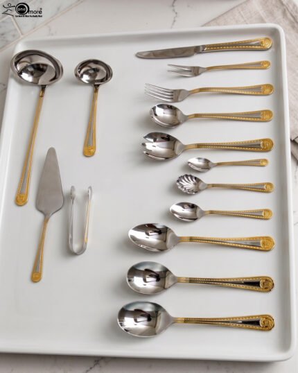 72-piece stainless steel cutlery set with gold trim handles and specialty serving utensils displayed on a white tray.