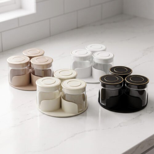 Four sets of ONE MORE 3-piece glass spice jars with trays sitting on a white marble countertop in beige, off-white, white, and black colors.