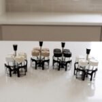 Four-piece clear glass spice jar set with lid options sitting in a black metal holder on a kitchen countertop.