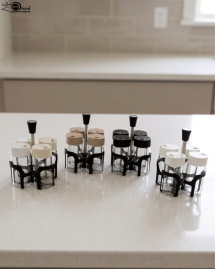 Four-piece clear glass spice jar set with lid options sitting in a black metal holder on a kitchen countertop.