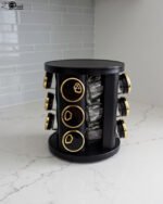Modern 12-piece rotating black and gold spice rack organizer with glass jars on a white marble kitchen countertop