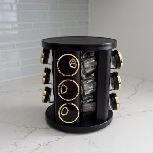 Modern 12-piece rotating black and gold spice rack organizer with glass jars on a white marble kitchen countertop