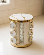 Modern 12-piece rotating black and gold spice rack organizer with glass jars on a white marble kitchen countertop