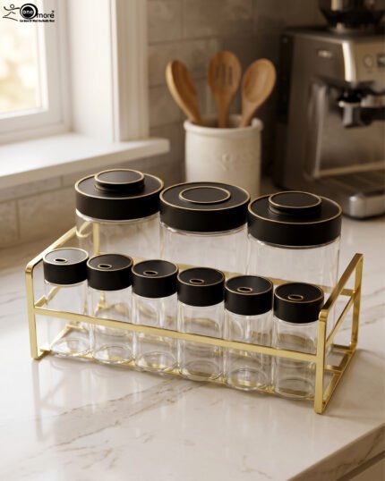 9-piece luxury glass spice jars with black gold-accented lids stored on a metallic gold wire rack on a marble kitchen countertop.