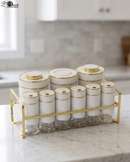 9-piece white ceramic and clear glass spice jar set with gold accents arranged in a gold metal rack on a marble countertop