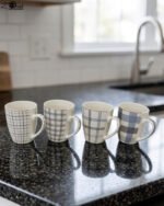 Set of 4 ceramic coffee mugs with blue and grey plaid grid patterns displayed on a kitchen countertop.