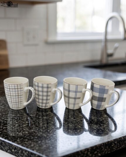 Set of 4 ceramic coffee mugs with blue and grey plaid grid patterns displayed on a kitchen countertop.