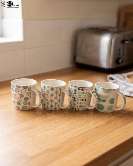 Four Onemore ceramic coffee mugs with teal and grey geometric patterns arranged on a wooden kitchen countertop.