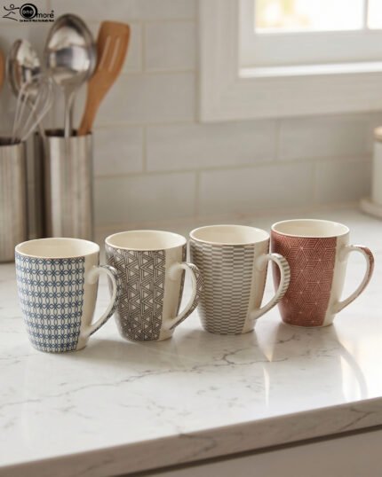 Set of four ceramic coffee mugs with unique geometric patterns in blue, grey, charcoal, and terracotta displayed on a kitchen counter.