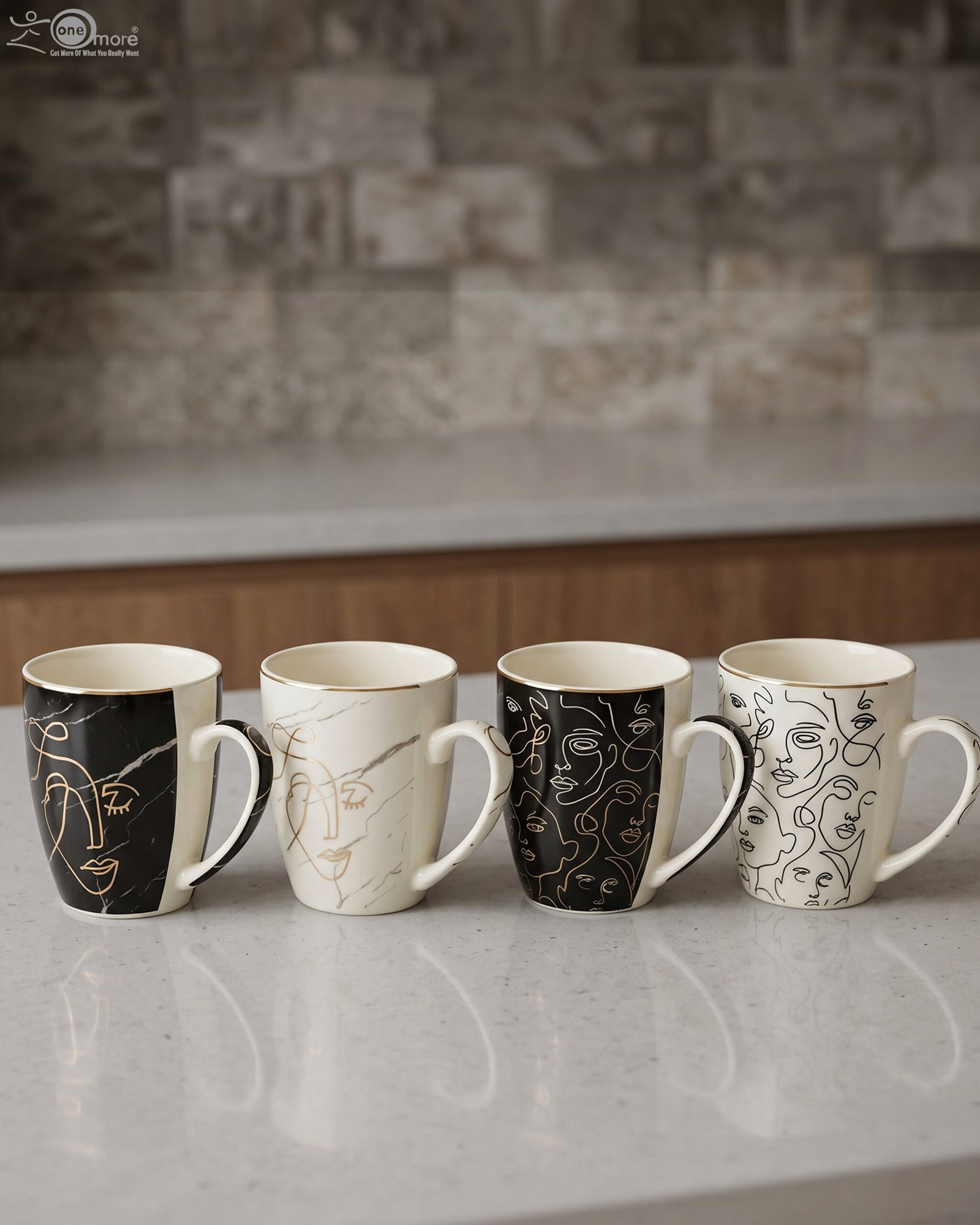 1 Set of 4 OneMore ceramic coffee mugs featuring abstract face line art in black, white, and gold on a kitchen countertop.