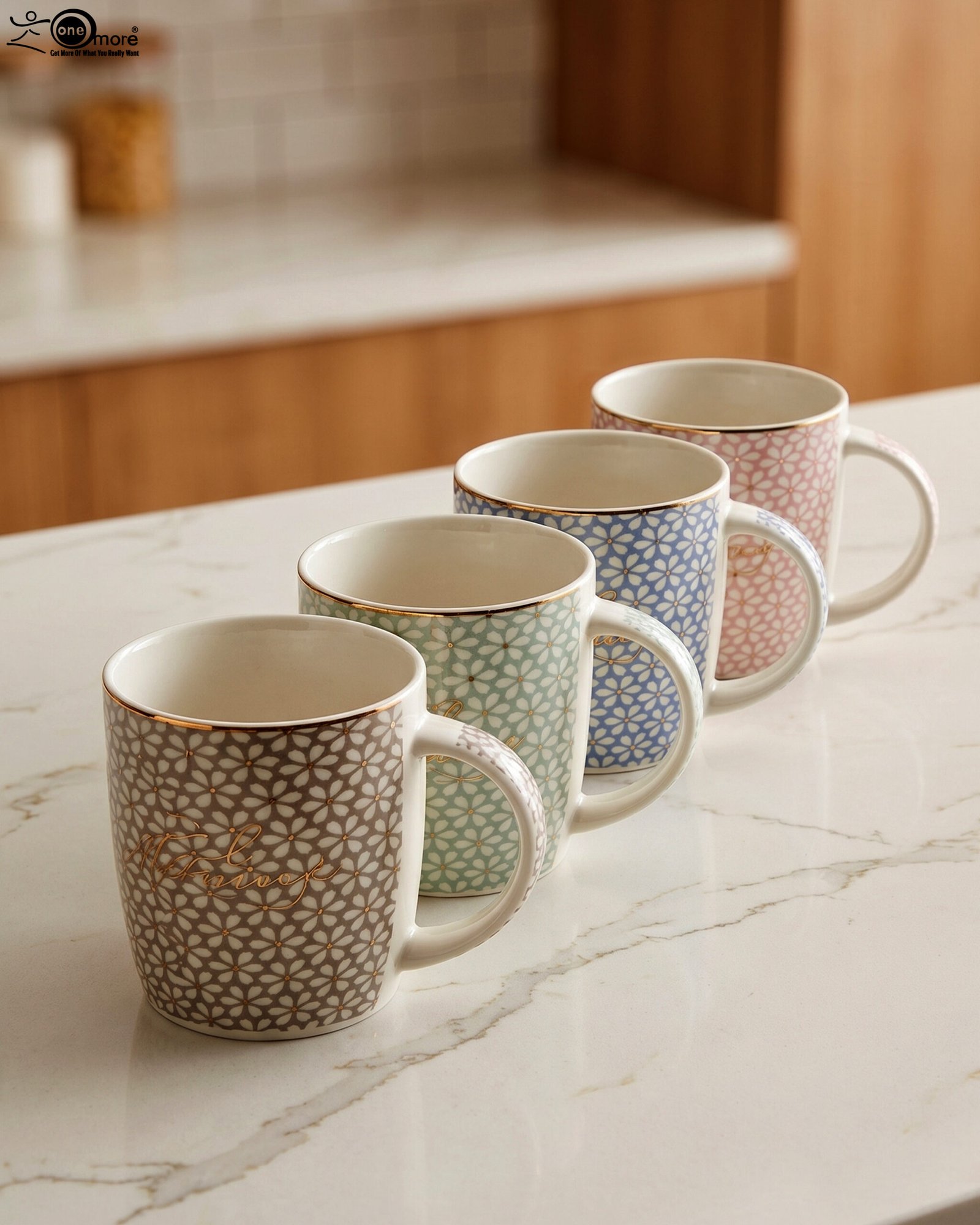 1 Four ceramic coffee mugs with pastel floral patterns in grey, green, blue, and pink featuring gold rims on a marble kitchen countertop.