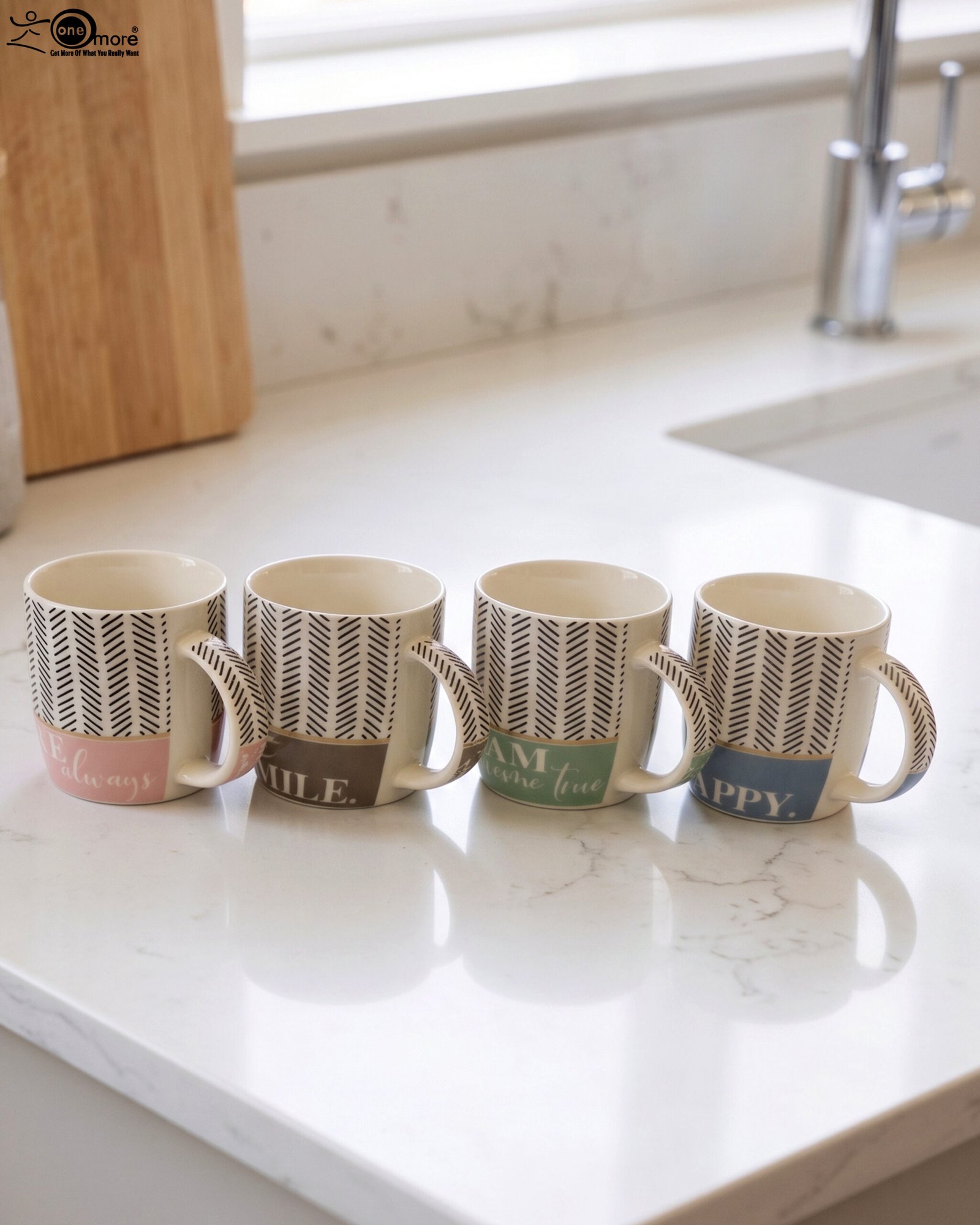 1 Four ceramic coffee mugs with black herringbone chevron patterns and colorful inspirational text labels lined up on a marble kitchen countertop.