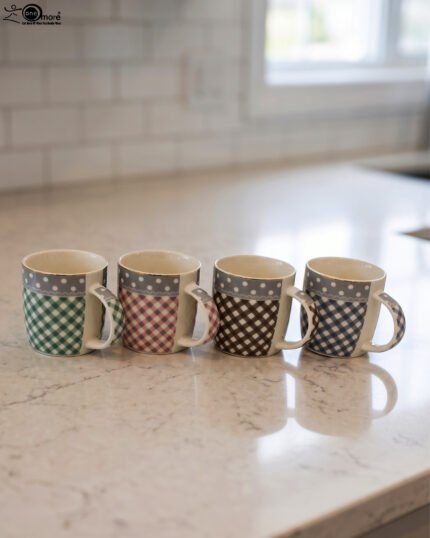 Four ceramic coffee mugs with gingham and polka dot patterns lined up on a marble countertop