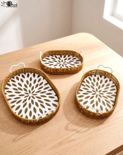 Set of 3 oval woven rattan serving trays with white handles and a modern geometric floral pattern base resting on a wooden table.