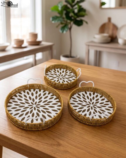 Set of 3 round handwoven rattan serving trays with white base patterns and handles resting on a wooden table