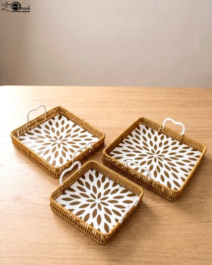 3-piece handwoven rattan serving tray set with white floral printed base and white handles on a wooden table.
