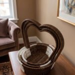 Nested set of three brown and white handwoven rattan trays featuring tall heart-shaped handles on a wooden table