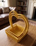 Set of 3 yellow woven rattan nesting trays with high arched handles stacked on a wooden coffee table.