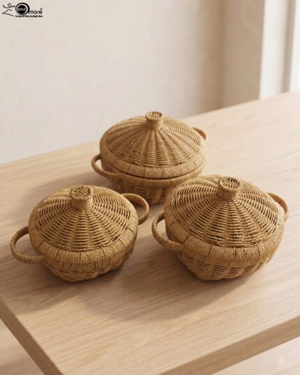 3-piece handwoven natural rattan basket set with fitted lids and side handles sitting on a light wooden table