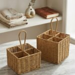Two handwoven rattan spoon holders with four divided compartments and loop handles sitting on a marble table.