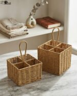 Two handwoven rattan spoon holders with four divided compartments and loop handles sitting on a marble table.