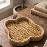 Handwoven light brown rattan fruit dish shaped like an apple resting on a rustic wooden table