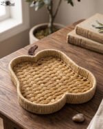 Handwoven light brown rattan fruit dish shaped like an apple resting on a rustic wooden table