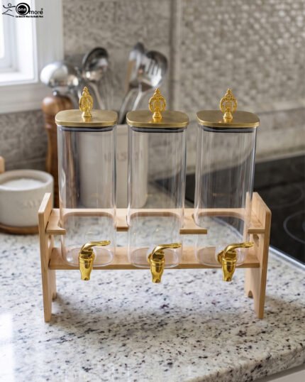 Triple clear acrylic beverage dispenser set on a wooden stand with gold spigots and decorative finial tops on a kitchen counter